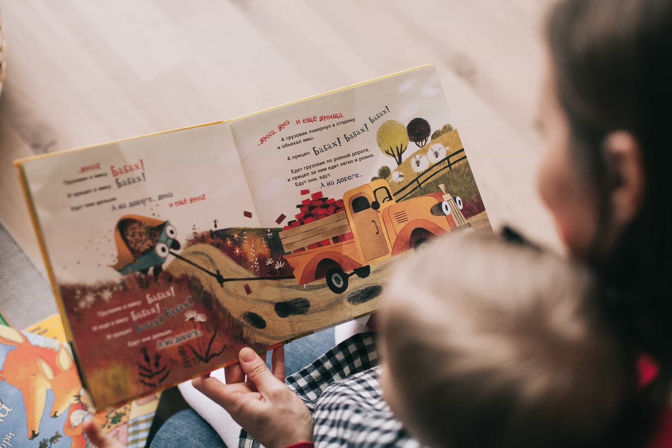 top down view of a child with blonde hair looking at a children's book that is open.